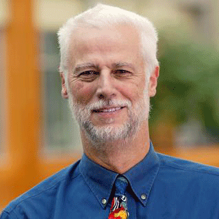 Richard Ladner, a white man with white hair and beard. He wears a blue button-down shirt and a colorful tie and is smiling warmly.