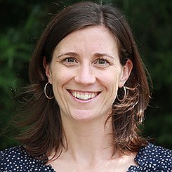 Headshot of Leah Findlater, smiling warmly. She is a white woman with brown hair and wears a blue and white patterned shirt.
